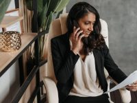 Woman reviewing documents while on a phone call in stylish office setting.