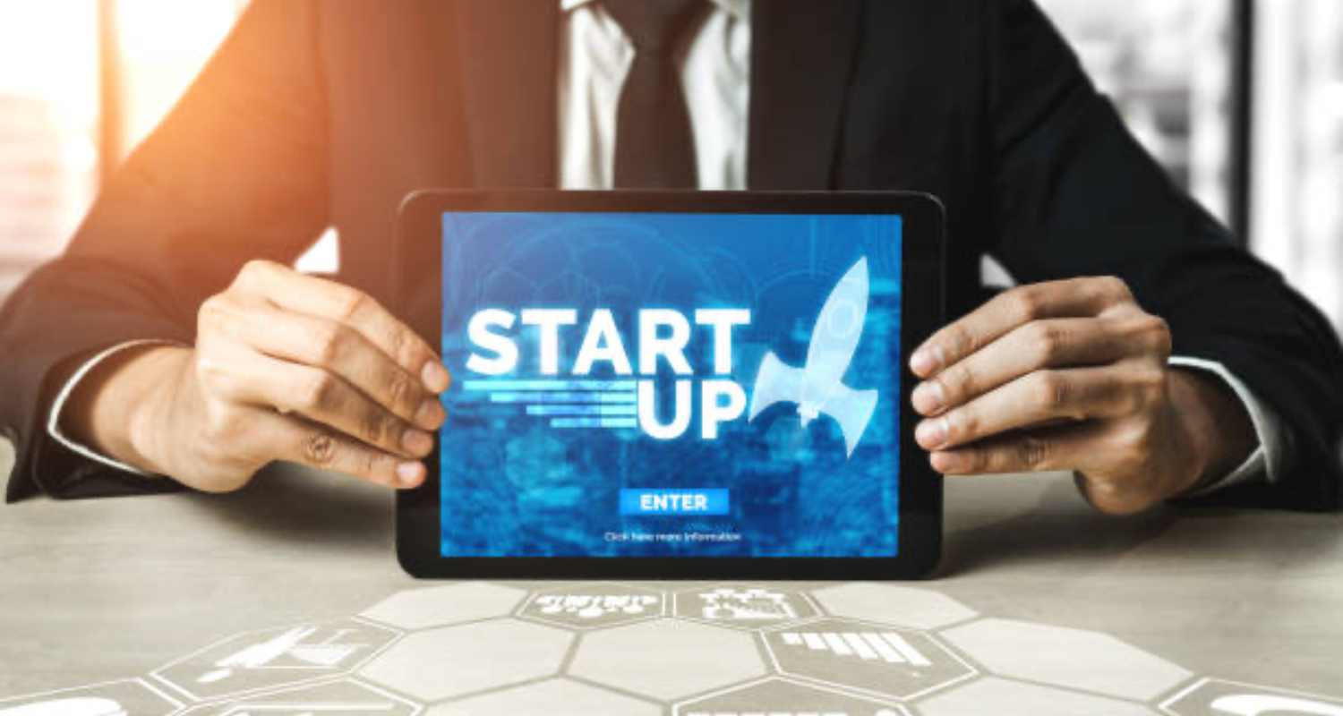 A business professional holding a tablet with "STARTUP" and a rocket icon, symbolizing innovation and growth in the startup world.